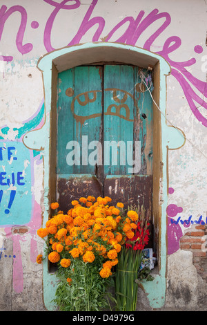 Mazzi di fiori nella parte anteriore del vano porta a spiovente Circondato da colorati graffiti in Ocotlan, Oaxaca, Messico. Foto Stock