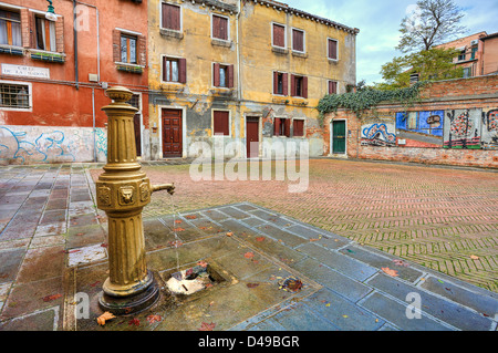 La pompa dell'acqua sul cortile tra il vecchio tradizionale veneziano case colorate a Venezia, Italia. Foto Stock