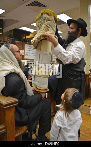 Con un giovane ragazzo osservando la Torah è coperto Torah prima che venga restituito al Santo Ark. Sede Lubavitch Brooklyn Foto Stock