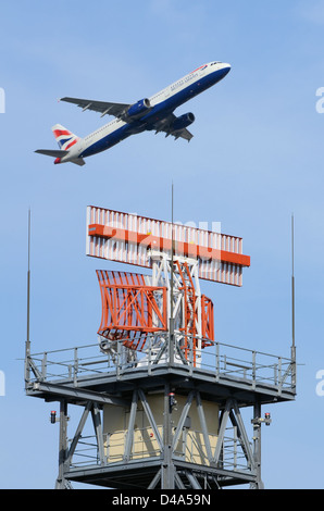 L'antenna radar per il controllo del traffico aereo presso l'aeroporto di Londra Heathrow LHR UK è sorvolata da un aereo di linea Boeing 777 della British Airways Foto Stock