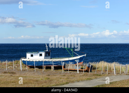 Vecchio di legno barca da pesca tirato verso l'alto sopra la spiaggia sullo Stretto di Magellano . Punta Arenas, Cile. Foto Stock