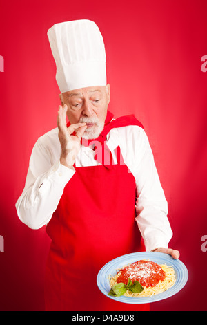 Chef italiani rende gli spaghetti. Sfondo rosso Foto Stock