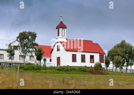 Tipica rurale chiesa islandese schierandosi in casa a nuvoloso giorno Foto Stock