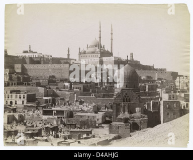 Questa immagine raffigura la Cittadella del Cairo vista da un cimitero, che mostra la grandezza storica e architettonica della città. La Cittadella, una fortezza islamica medievale, si distingue con i suoi minareti e moschee, che dominano lo skyline del Cairo. Foto Stock