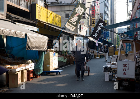 La mattina presto strada costeggiata da negozi e ristoranti e i lavoratori che si spostano su vicino a Tsukiji Commercio all'ingrosso Mercato del Pesce di Tokyo. Foto Stock