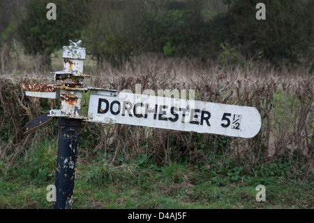 Inglese cartello stradale. "Dorchester 5 ½ miglia". Un vecchio fatiscente fingerpost accanto a un vicolo del paese in zone rurali Dorset, Inghilterra, Regno Unito. Foto Stock