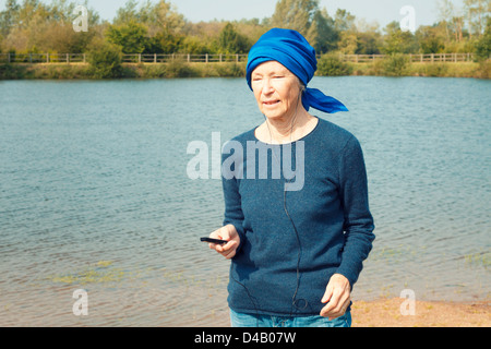 Senior donna utilizzando un lettore mp3 all'esterno. Foto Stock