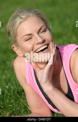 Donna sdraiati sull'erba ridere Foto Stock