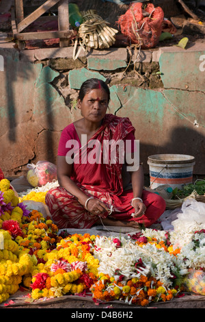 Una donna vendita di ghirlande di fiori guarda la telecamera in Kolkata, India Foto Stock