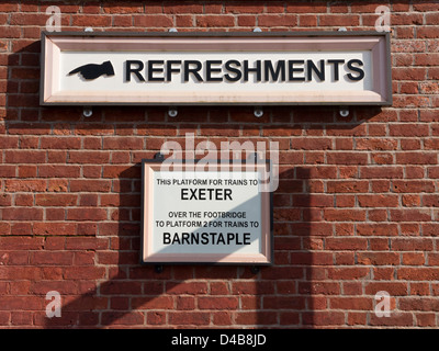 Vecchi segni a Crediton stazione ferroviaria che mostra i rinfreschi e informazioni di piattaforma a Crediton, Devon, Inghilterra Foto Stock