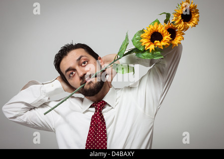 Ritratto di un giovane uomo barbuto con girasoli nella sua bocca Foto Stock