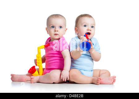 Simpatici Baby girl e ragazzo giocando giocattoli musicali. Isolato su sfondo bianco Foto Stock