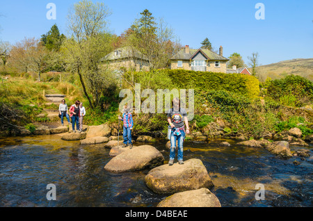 Una famiglia che attraversa il West Dart River su Dartmoor a Dartmeet, Devon, Inghilterra. Foto Stock