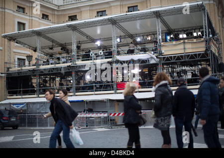 Persone (anteriore) guardare la televisione reporter che stanno su una piattaforma che si affaccia su Piazza San Pietro nella Città del Vaticano, Vaticano, 11 marzo 2013. Il nuovo papa sarà eletto nel conclave. Foto: MICHAEL KAPPELER Foto Stock