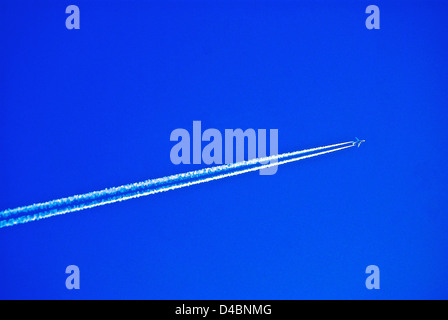 Un High flying JET RENDE CONTRAILS attraverso un cielo blu SUL SUO VIAGGIO Foto Stock