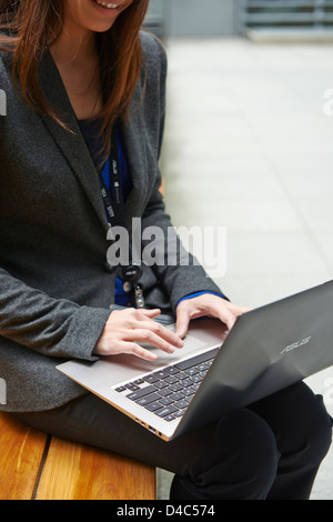 Una donna di affari sul nuovo ASUS Zenbook, un ultra-portatile sottile con una finitura metallica, altoparlanti stereo e tasti retroilluminati. Foto Stock