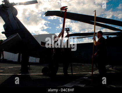 I membri dell'equipaggio di un elicottero di combattimento di mare Squadron 23 "Wild Card" slacciare le pale di un MH-60S Knighthawk elicottero Foto Stock