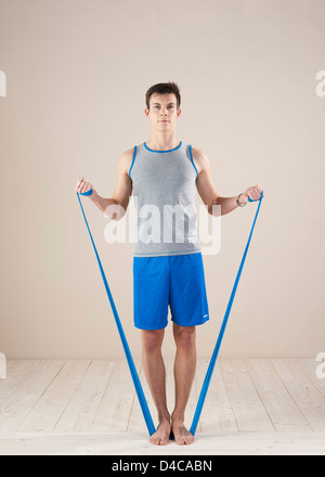 Giovane uomo a fare gli esercizi con un cinturino di ginnastica Foto Stock