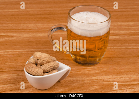 Birra e noccioline su una barra di legno counter Foto Stock