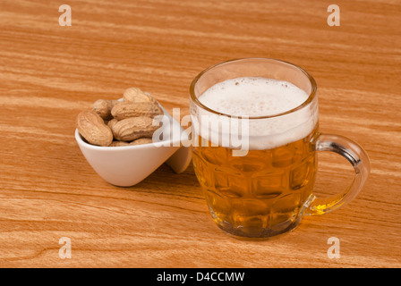 Birra e noccioline su una barra di legno counter Foto Stock