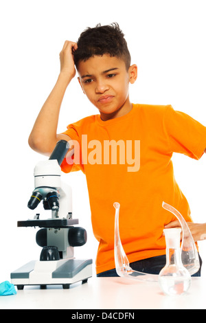 Black Boy perplesso in chimica classe con microscopio e lab apparecchiature in vetro Foto Stock