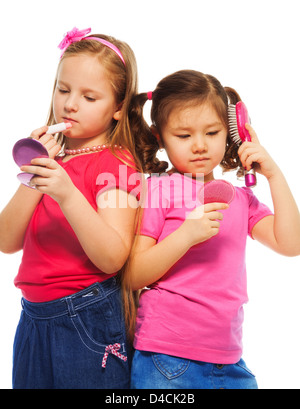 Due ragazze e caucasici Asian a giocare per essere grande come la madre e la spazzolatura che compongono il viso, isolato su bianco Foto Stock