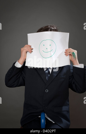 Ragazzo che ricopre la faccia con il disegno della faccia felice Foto Stock