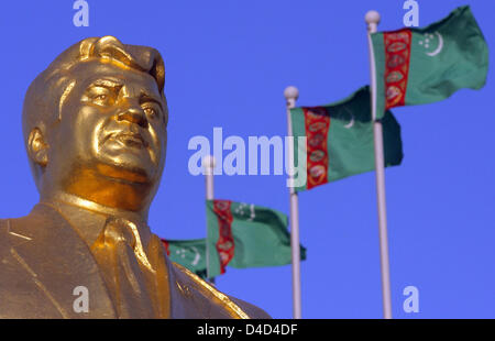 Bandiere turkmeno in onda il vento dietro uno dei tanti golden statue dell ex Presidente turkmeno per la vita, Saparmurat Niyazov nel capitale Aşgabat, Turkmenistan, 25 febbraio 2008. Niyazov morto nel dicembre 2006, aveva il suo popolo adorarlo come Türkmenbaşy il significato di "Padre del Turkmeni'. Foto: Tim Brakemeier Foto Stock