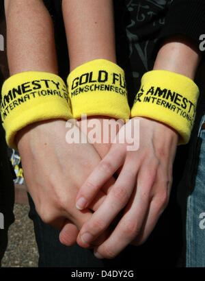 Tre membri dell organizzazione per i diritti umani Amnesty International (AI) usura wristlets lettura 'Gold fuer Menschenrechte" (letteralmente: "Gold per i Diritti Umani") e trattenere reciprocamente le mani all'inizio di un alternativi " Torcia Olimpica' a Friburgo in Germania il 3 maggio 2008. La torcia relè è andata in scena in segno di protesta contro la situazione dei diritti umani in Cina. Esso condurrà attraverso 25 m. Foto Stock