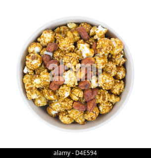 Vista dall'alto di una ciotola riempita con caramello di popcorn e arachidi su uno sfondo bianco. Foto Stock
