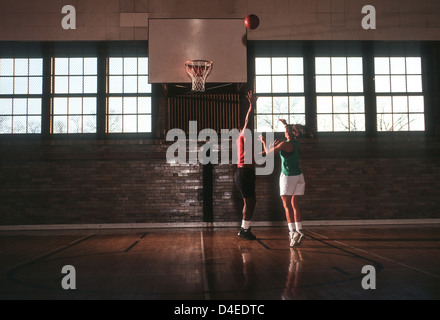 Un ragazzo e una ragazza a giocare a basket in palestra. Foto Stock