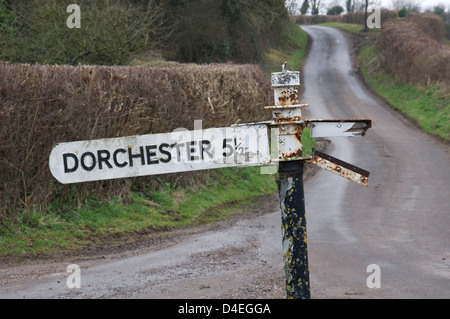 Inglese cartello stradale. "Dorchester 5 ½ miglia". Un vecchio fatiscente fingerpost accanto a un vicolo del paese in zone rurali Dorset, Inghilterra, Regno Unito. Foto Stock