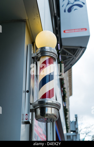 Un barbiere illuminato segnali polo il negozio è aperto e pronto per il business. Foto Stock