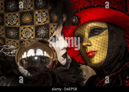 Due donne vestite per il Carnevale di Venezia detiene una sfera di metallo in cui San Marco e le persone sono riflesse, Italia Foto Stock