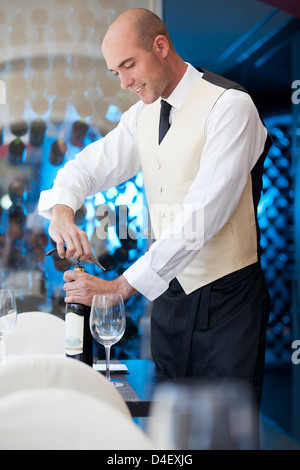 Cameriere stappo bottiglia di vino nel ristorante Foto Stock