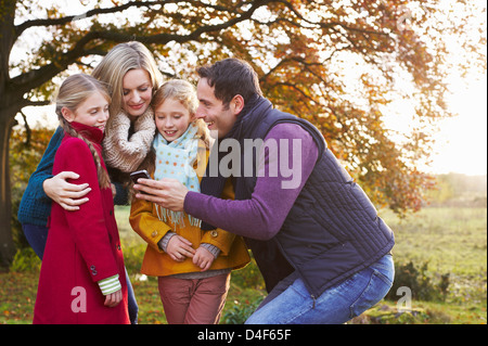 La famiglia tramite telefono cellulare insieme all'aperto Foto Stock
