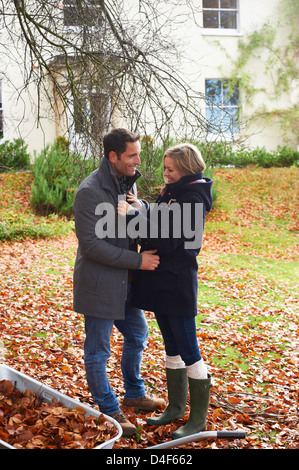 Coppia sorridente in piedi in foglie di autunno Foto Stock