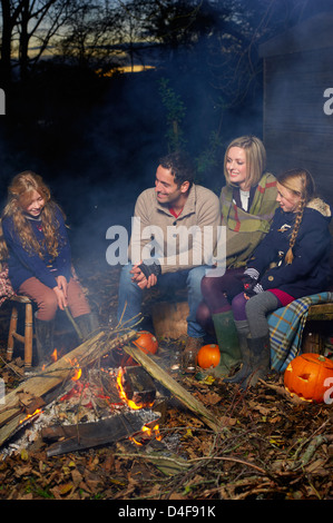 Famiglia relax intorno al fuoco di notte Foto Stock