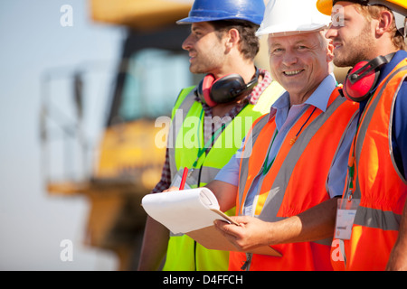 Imprenditore e lavoratori parlando sul sito Foto Stock