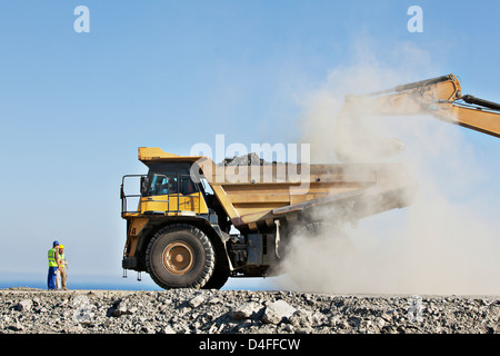 I lavoratori di supervisionare digger e carrello in cava Foto Stock