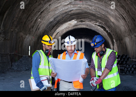 Lavoratori e imprenditore con blueprint nel tunnel Foto Stock