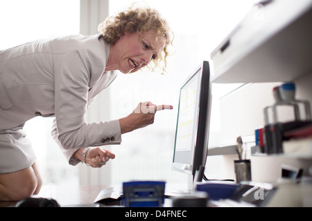 Imprenditrice a urlare contro il computer in ufficio Foto Stock