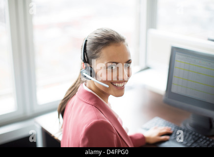 Imprenditrice che indossa la cuffia alla scrivania Foto Stock