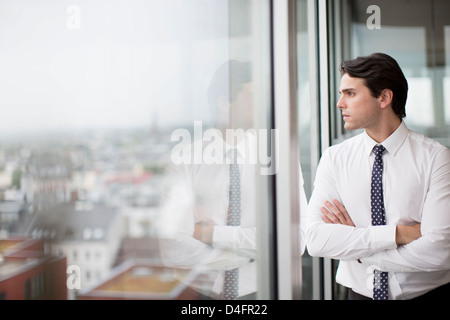 Imprenditore a guardare fuori dalla finestra di ufficio Foto Stock