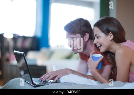 Paio utilizzando laptop insieme sul letto Foto Stock