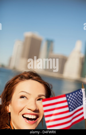 La donna sventola bandiera americana dal paesaggio urbano della città Foto Stock