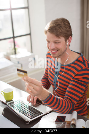 L'uomo nelle cuffie shopping sul computer portatile Foto Stock