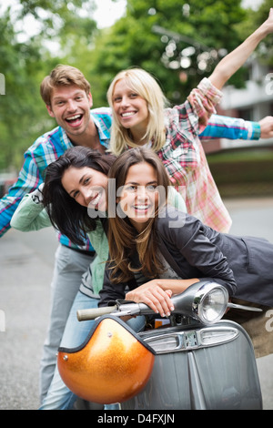 Gli amici di sorridere su scooter all'aperto Foto Stock