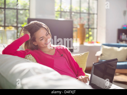 Donna che utilizza sul computer portatile sul divano Foto Stock