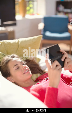 Donna di giocare con i videogiochi su divano Foto Stock